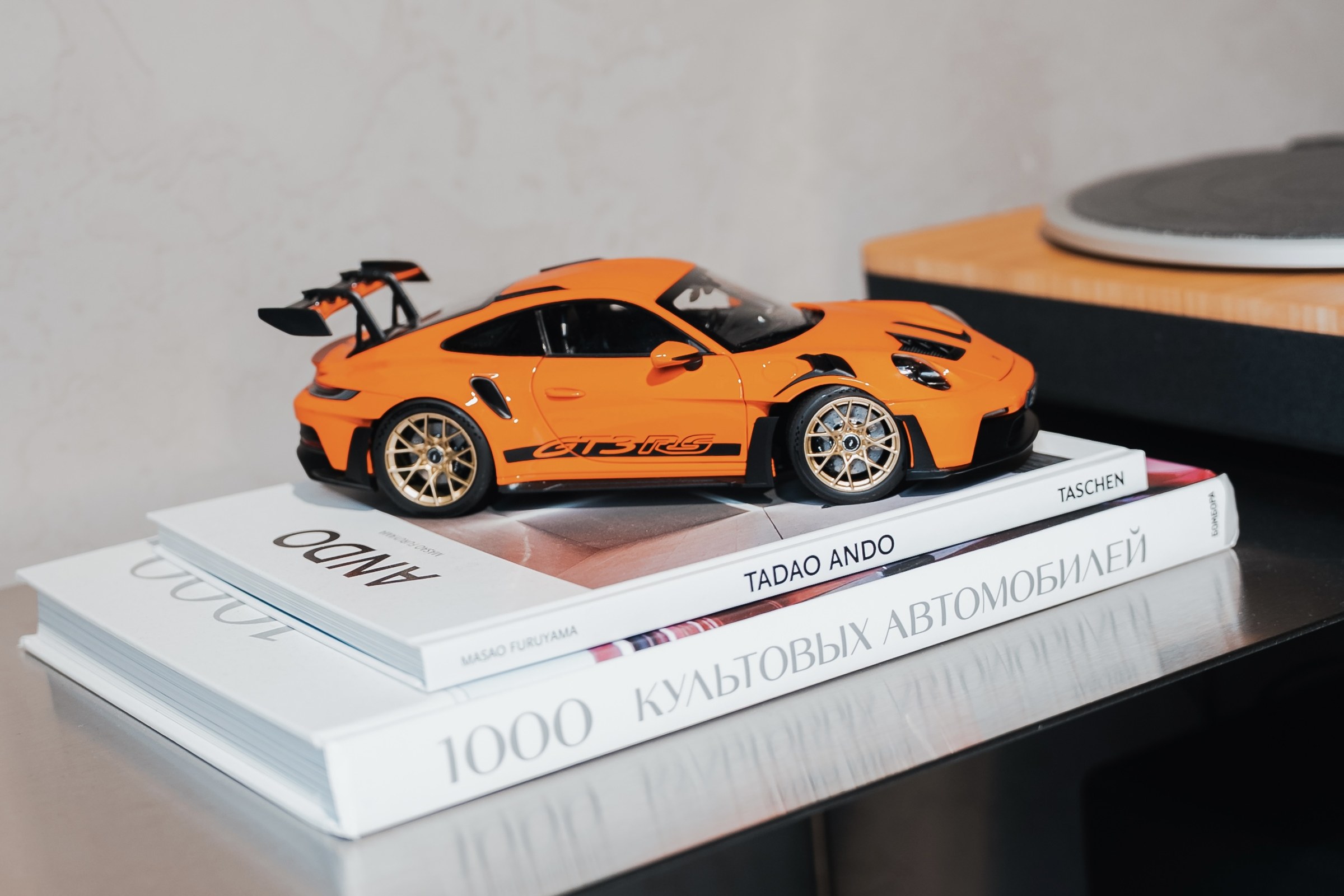 Модель Porsche 911 GT3 RS на стопке книг об автомобилях